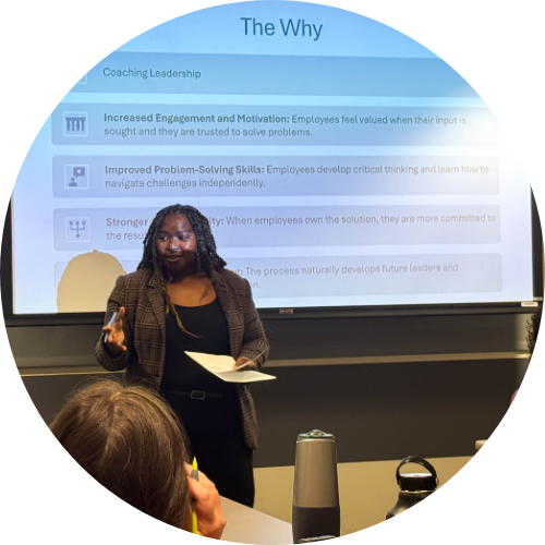 A speaker presents coaching leadership concepts, emphasizing employee engagement and problem-solving skills in a workplace setting.