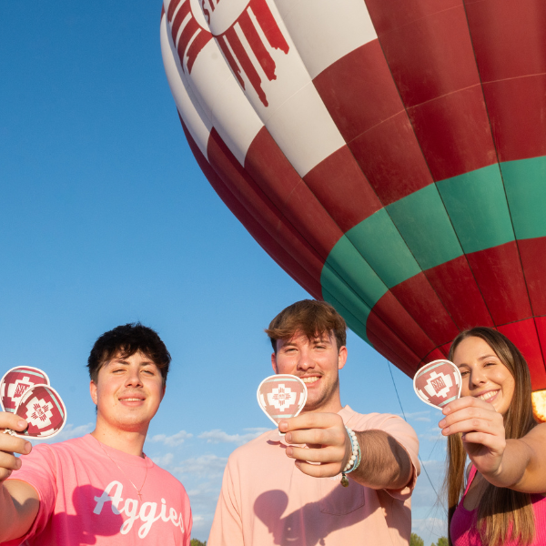 Students infront of NMSU Air Ballon holding stickers